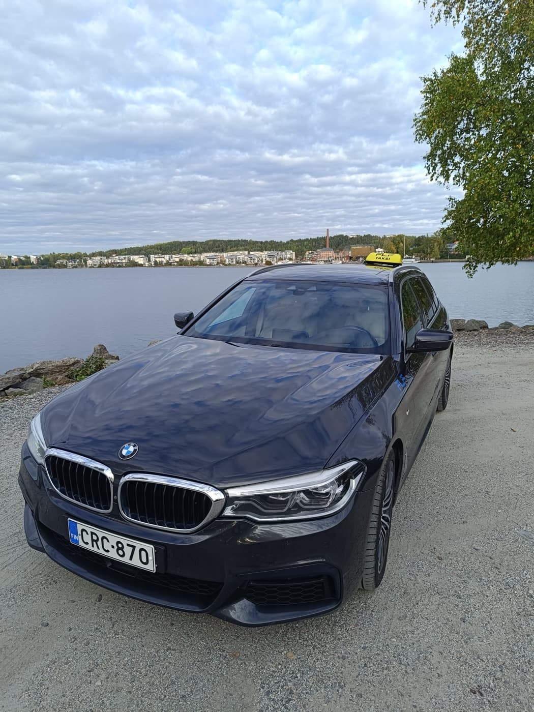 Tummansininen BMW 5-sarjan taksi Vesijärven rannalla